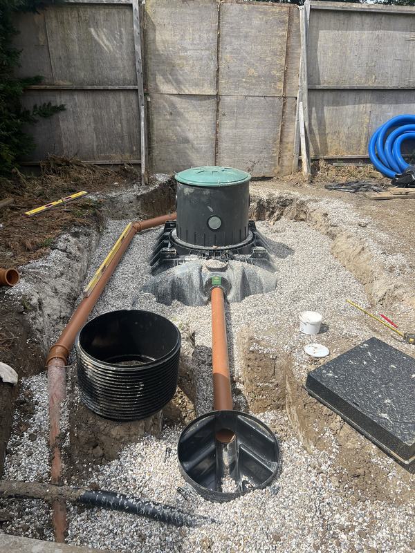 Sewage treatment plant and inspection chambers installed in a gravel bed with orange drainage pipework